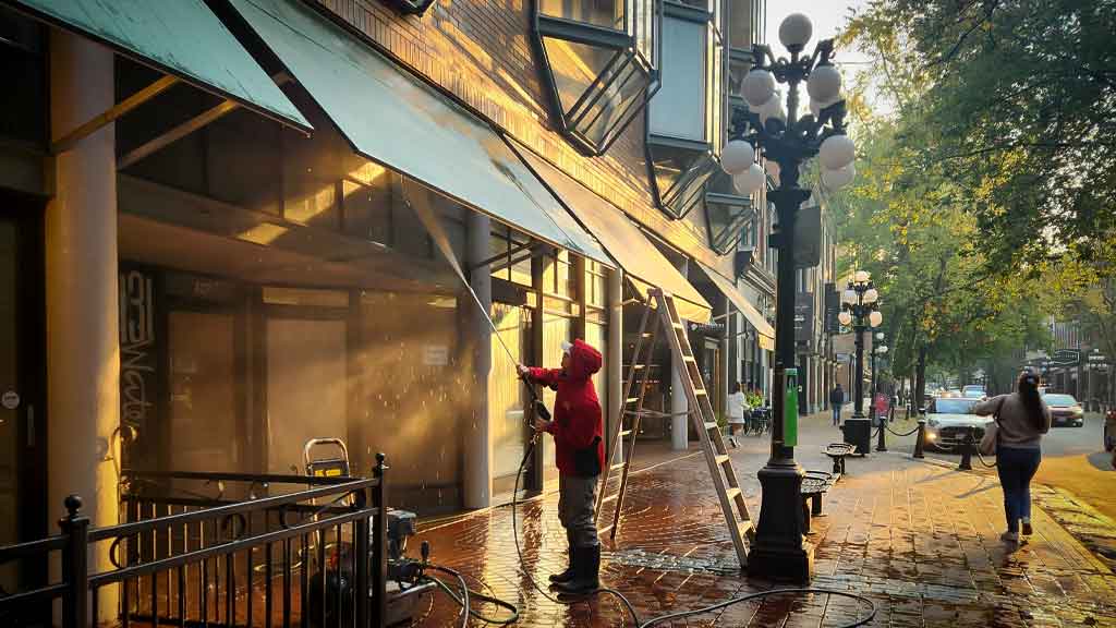 Maple Washing Employee using a pressure washer to clean under awnings for a local business.