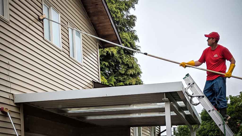 Member of the Maple Washing Team brush washing a home with eco friendly chemicals