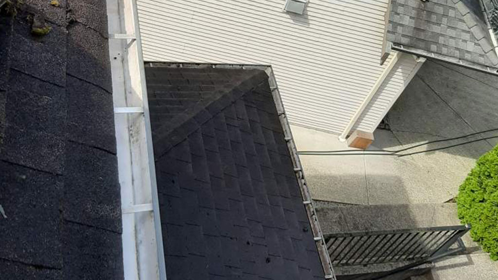 Seasonal Exterior Maintenance team performing gutter cleaning on a residential home to prevent water damage.