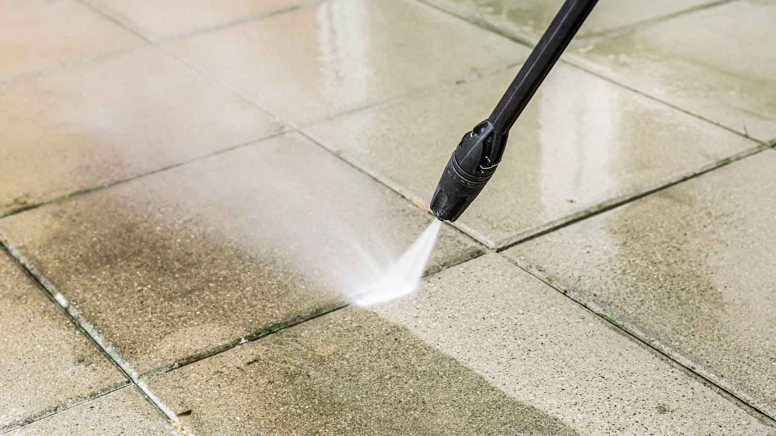 Power Washing vs. Pressure Washing Close up of a pressure washer nozzle cleaning stone pavers.