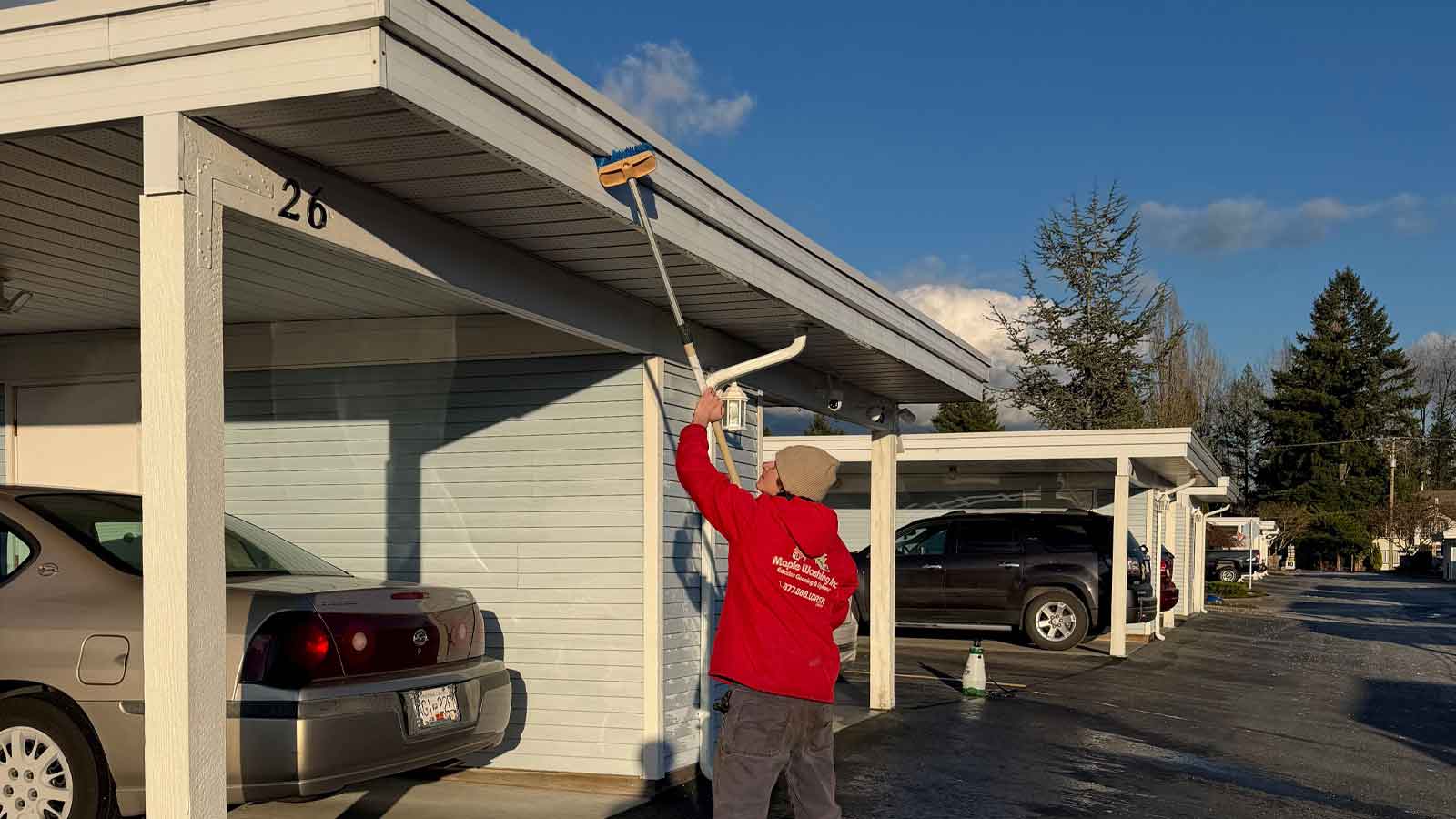 Maple Washing employee brush washing siding of a garage covering.